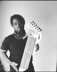 a black and white photo of a man holding a wooden guitar